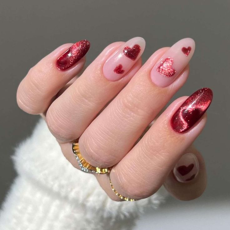 Red heart nail art design on long nails, featuring shimmer and nude base. Trendy manicure idea for Valentine's or romantic looks.