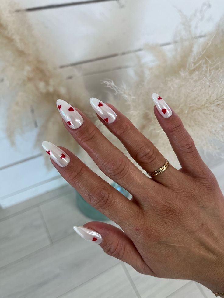 Elegant white nails with red heart designs, perfect for a romantic look. Ideal Valentine's nail art inspiration.