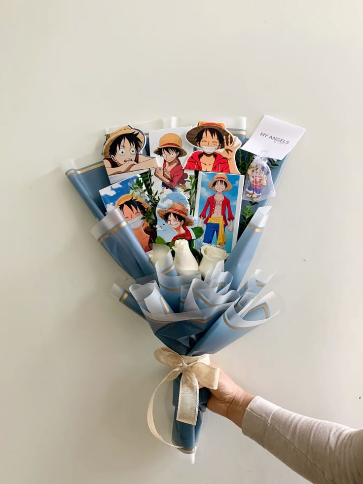 Anime character bouquet with blue wrapping featuring various images, ideal gift for fans and special occasions.