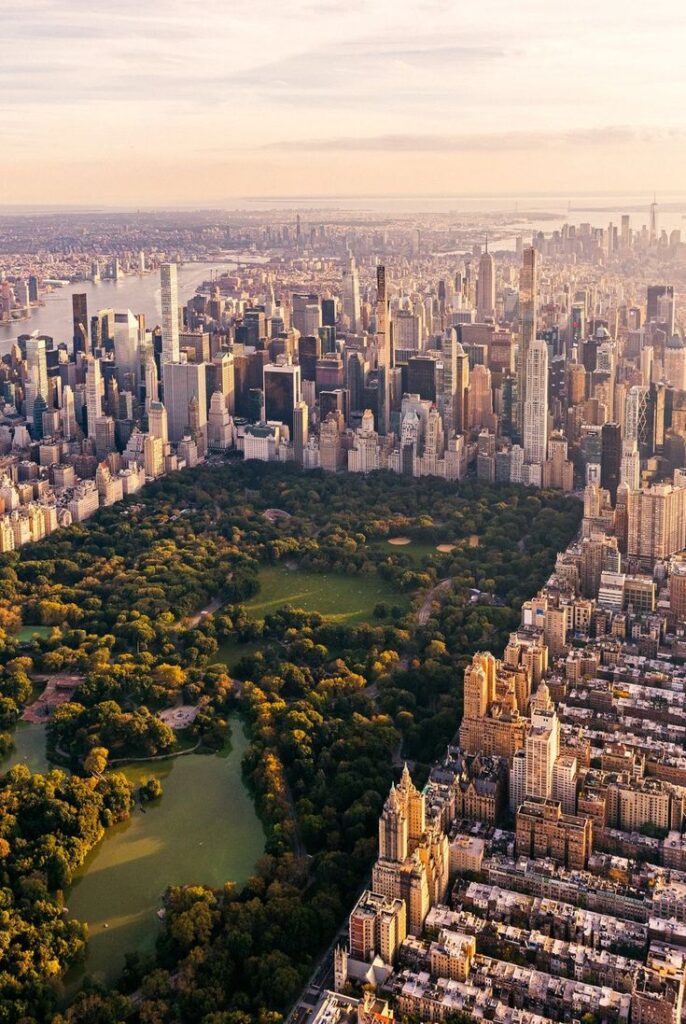 Aerial view of New York City's Central Park amid the urban skyline at sunset, showcasing the contrast of nature and architecture.