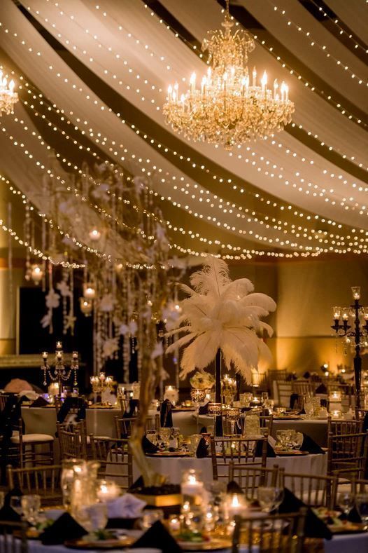 Elegant wedding reception with chandeliers, draped lights, and lavish table settings for a luxurious celebration ambiance.