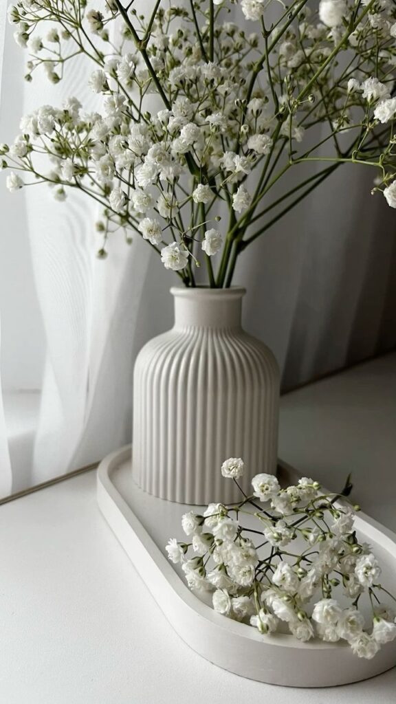 Elegant white flowers in a ribbed vase on a tray, creating a serene and minimalist decor ambiance.