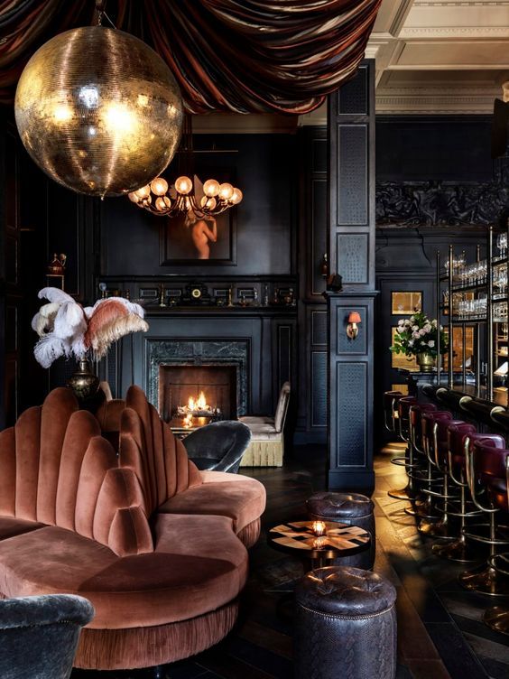 Luxurious vintage lounge with velvet seating, a grand chandelier, and cozy fireplace, creating an elegant, warm atmosphere.