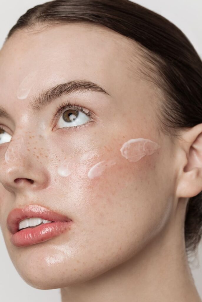 Close-up of a woman's face with skincare cream applied, showcasing natural beauty and skincare routine.