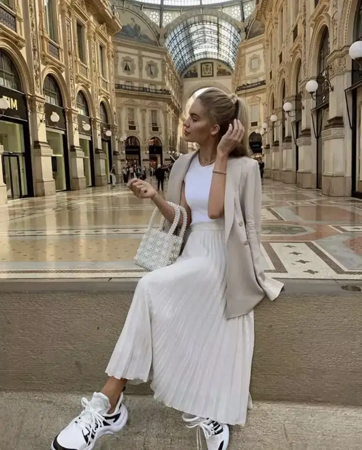 Fashionable woman in a white outfit and sneakers at a historic shopping gallery. Elegant style in an iconic architectural setting.