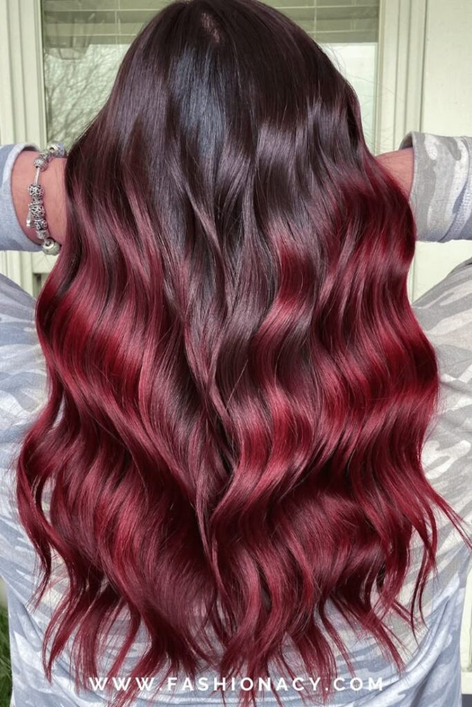 Wavy dark to red ombre hair with a glossy finish, showcasing a stylish and vibrant look for long locks.