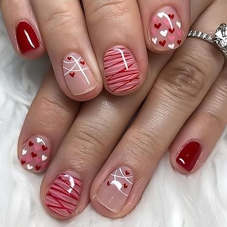 Romantic nail art with red and pink designs featuring hearts and stripes, perfect for Valentine's Day or a special occasion manicure.