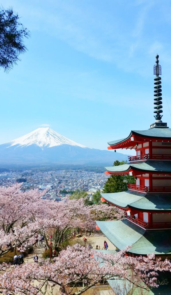 Pagoda with cherry blossoms and Mount Fuji in the background under a clear blue sky. Iconic Japanese scenery.