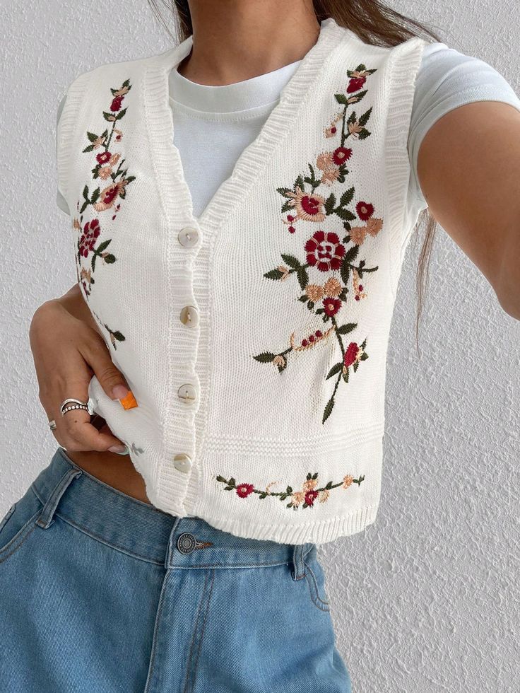 Woman in floral embroidered white vest and jeans, showcasing casual fashion style against a textured wall background.