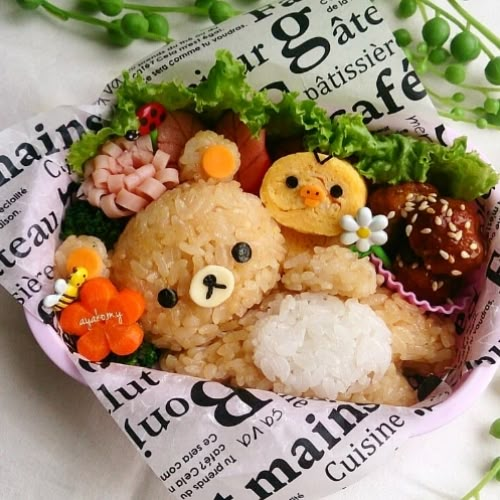 Cute bear-shaped rice bento with chick, flowers, and lettuce, arranged in a decorative lunch box. Fun and creative food art.