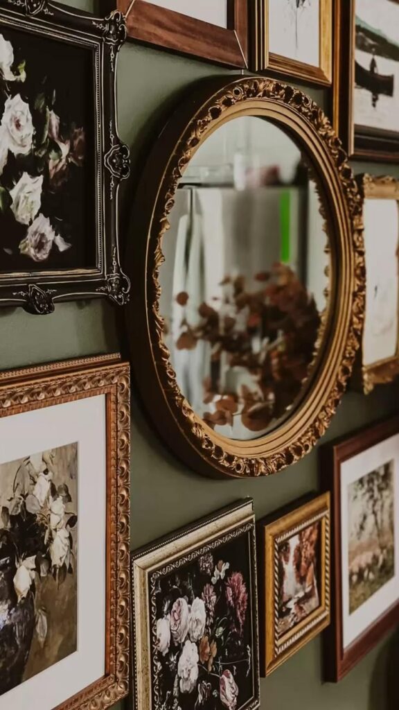 Elegant gallery wall with vintage frames and a decorative mirror on a green background.