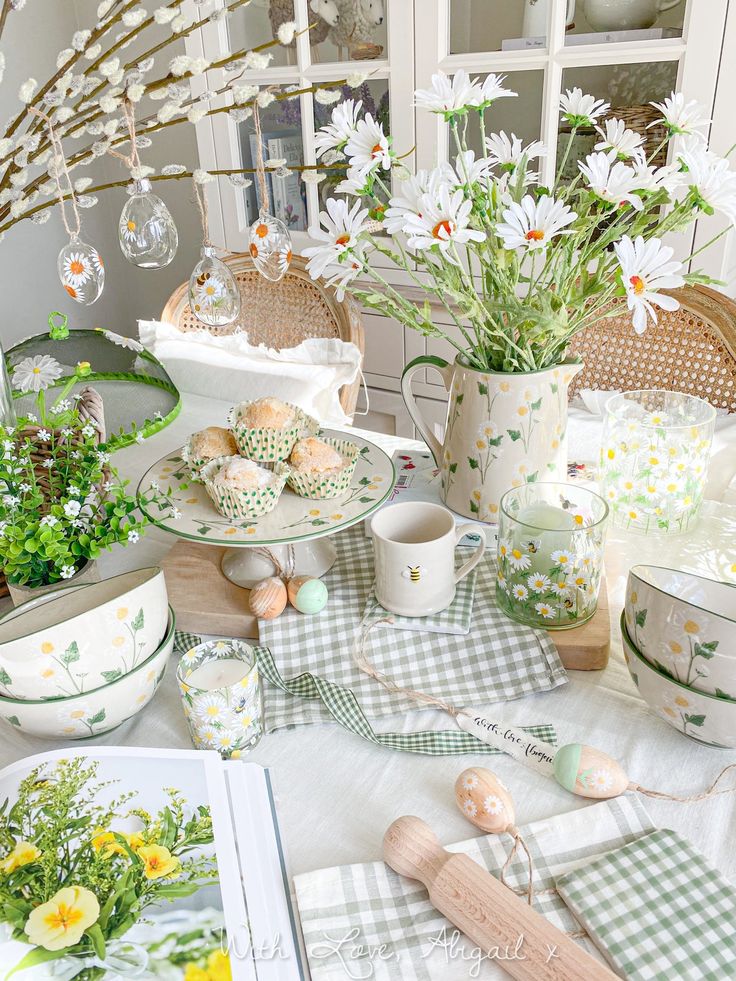 Charming spring table setting with daisies, muffins, and floral crockery. Cozy and inviting dining decor with nature-inspired elements.