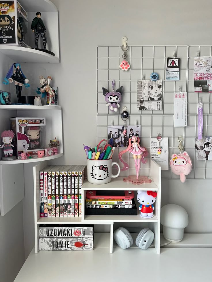 Cute anime-themed workspace with figures, manga books, and stationery, featuring Hello Kitty decor and character accessories.