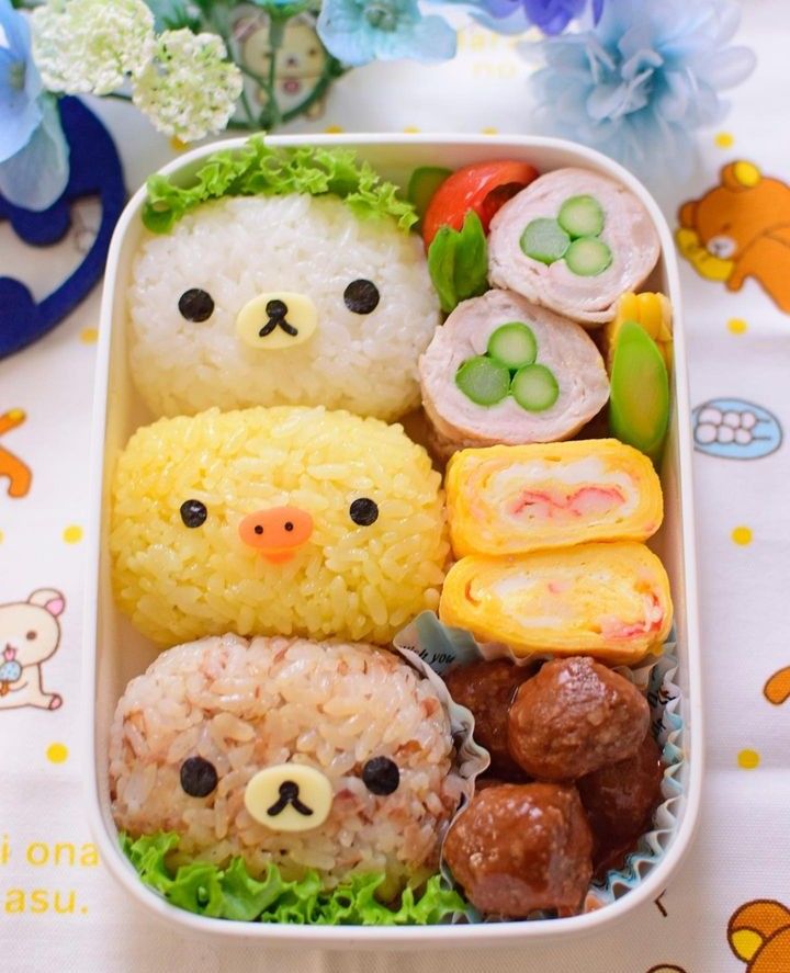 Cute character-themed bento box with rice, vegetables, and decorative food items, perfect for kids' lunches.