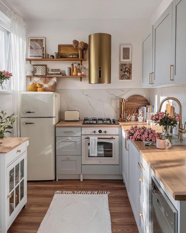 Stylish kitchen with white cabinets, wood countertops, gold accents, and pink floral decor for a cozy, modern look.