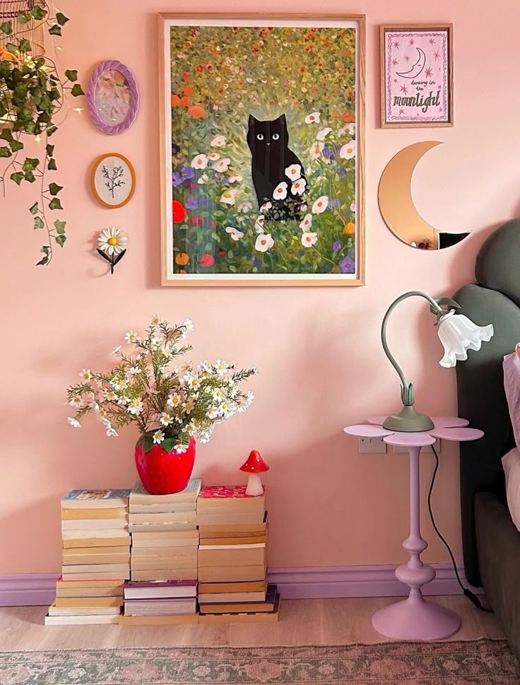 Cozy bedroom with cat painting, books, red vase with flowers, and eclectic wall decor. Warm, artistic ambiance.