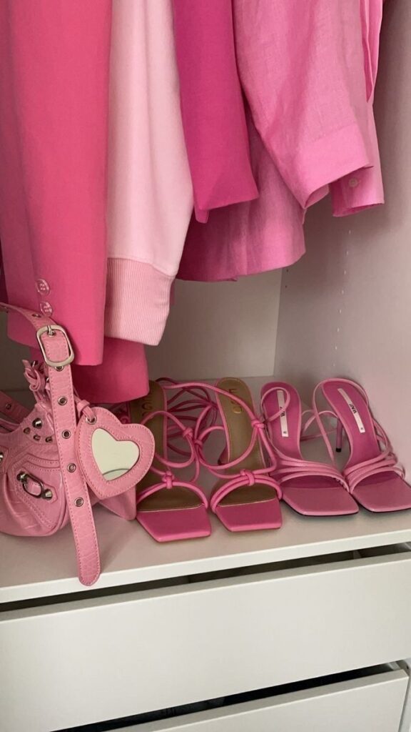 Pink wardrobe with dresses, sandals, and heart-shaped bag. Fashionable pink closet organization.