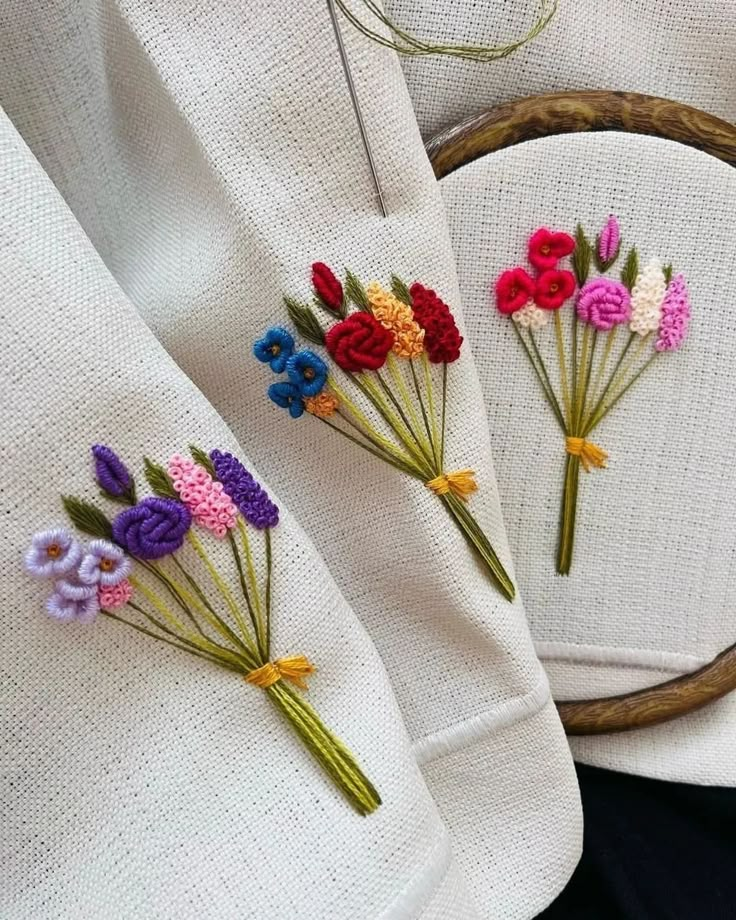 Colorful floral embroidery on fabric with needle, showcasing intricate handmade designs in hoops. Perfect for craft enthusiasts.