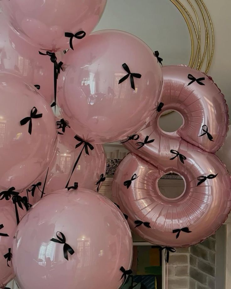 Pink balloons with black bows, including a large 8, creating a festive atmosphere. Perfect for a birthday party decoration.