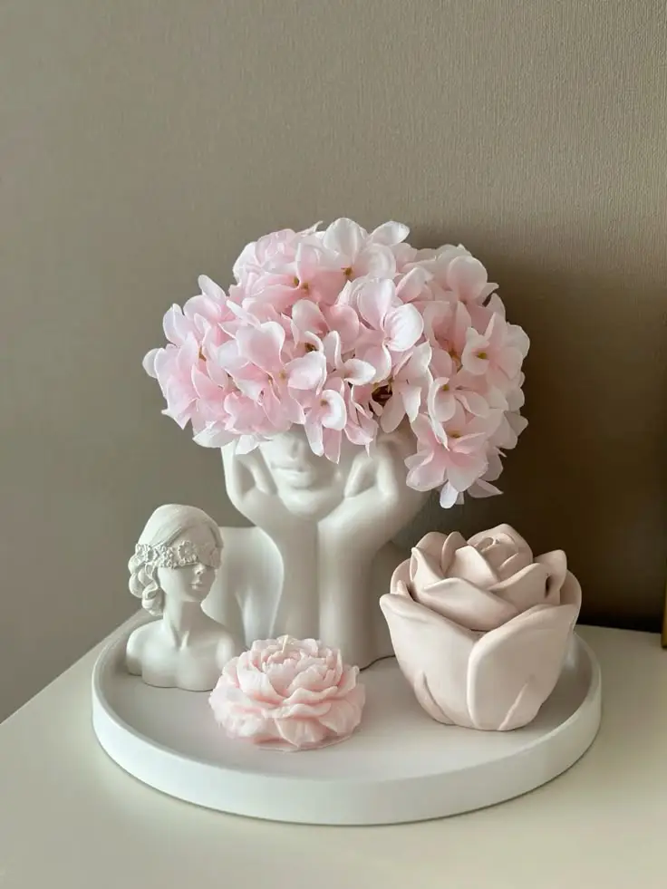 Elegant ceramic display with pink hydrangeas and delicate sculptures on a white tray, perfect for modern home decor.
