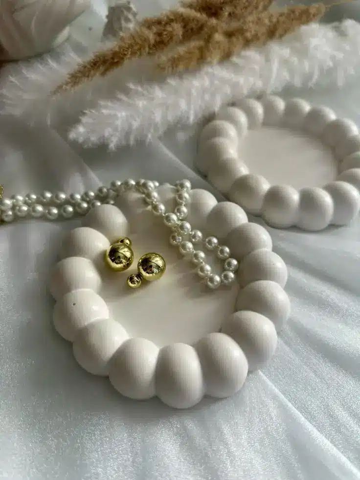 White decorative beads with gold accents and pearls on a soft satin background, creating an elegant and luxurious aesthetic.