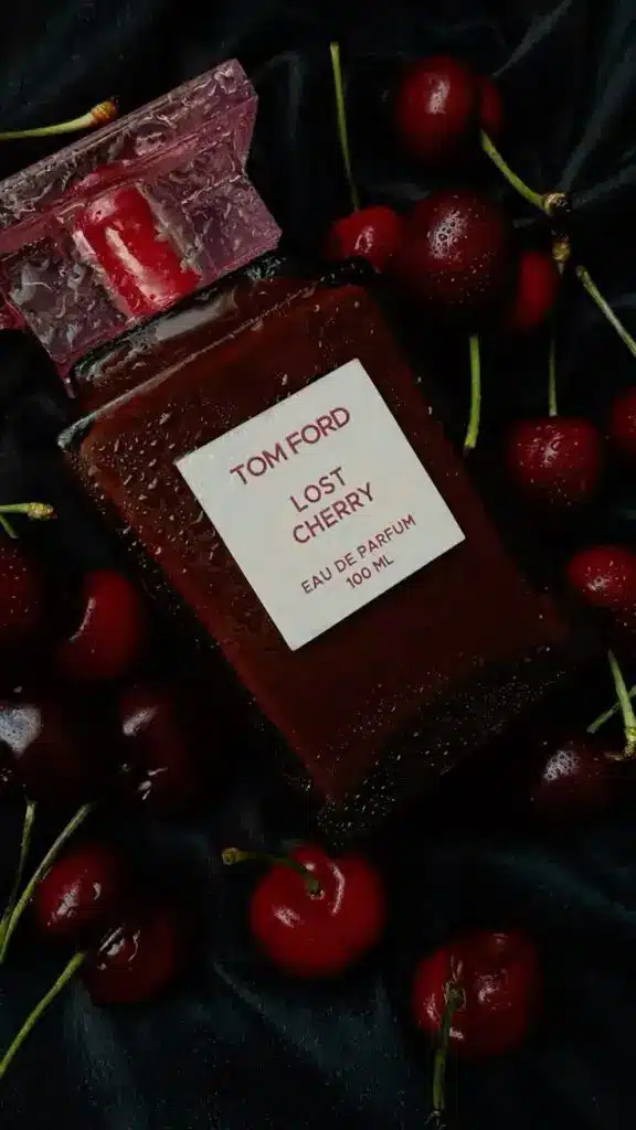 Tom Ford Lost Cherry perfume bottle surrounded by fresh cherries on a silky black background.