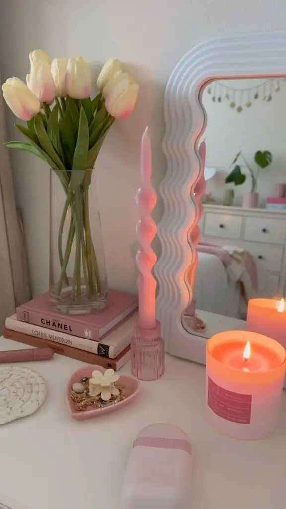 Cozy vanity setup with tulips, pink candles, and fashion books, creating a relaxing and stylish atmosphere.