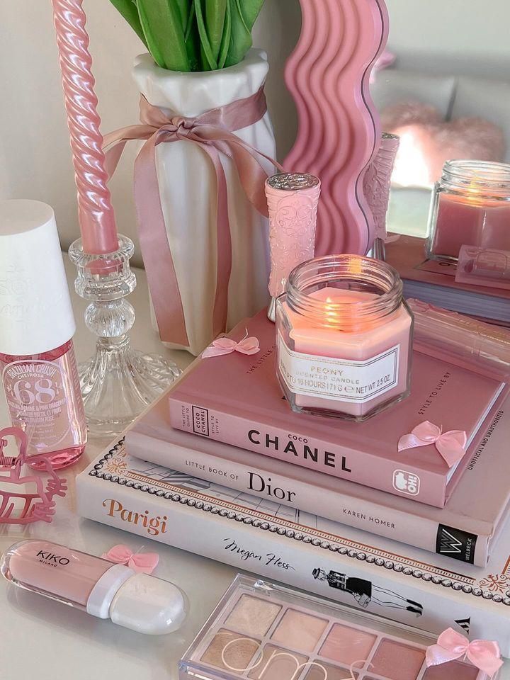 Elegant vanity with pink decor: books, candles, and makeup for a chic aesthetic. Feminine, stylish, and cozy vibes.