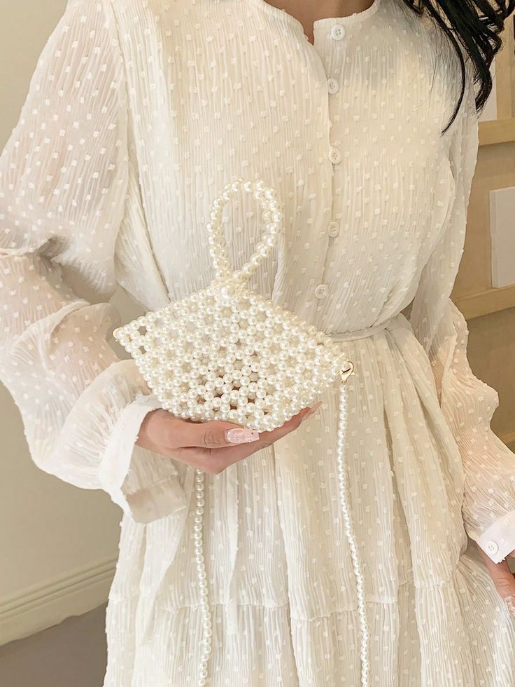 Woman in elegant white dress holding a trendy pearl handbag. Fashionable and chic style.