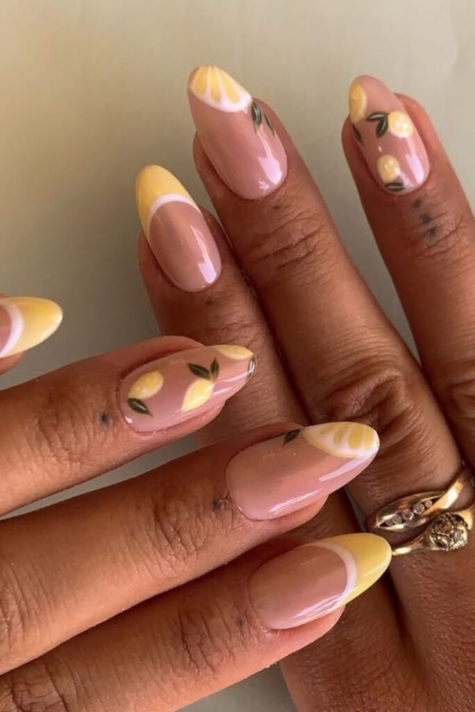 Elegant lemon-themed nail art with pastel yellow tips and lemon designs on oval nails, perfect for a fresh summer look.