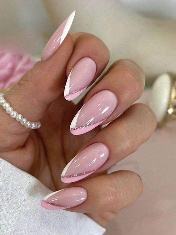 Elegant pink almond-shaped nails with white tips and delicate rhinestone accents, perfect for a chic and stylish manicure.