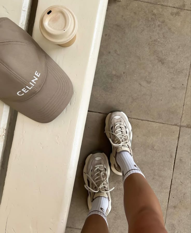 Casual street style: beige cap, latte, chunky white sneakers, and socks on pavement. Fashion essentials for a relaxed day out.