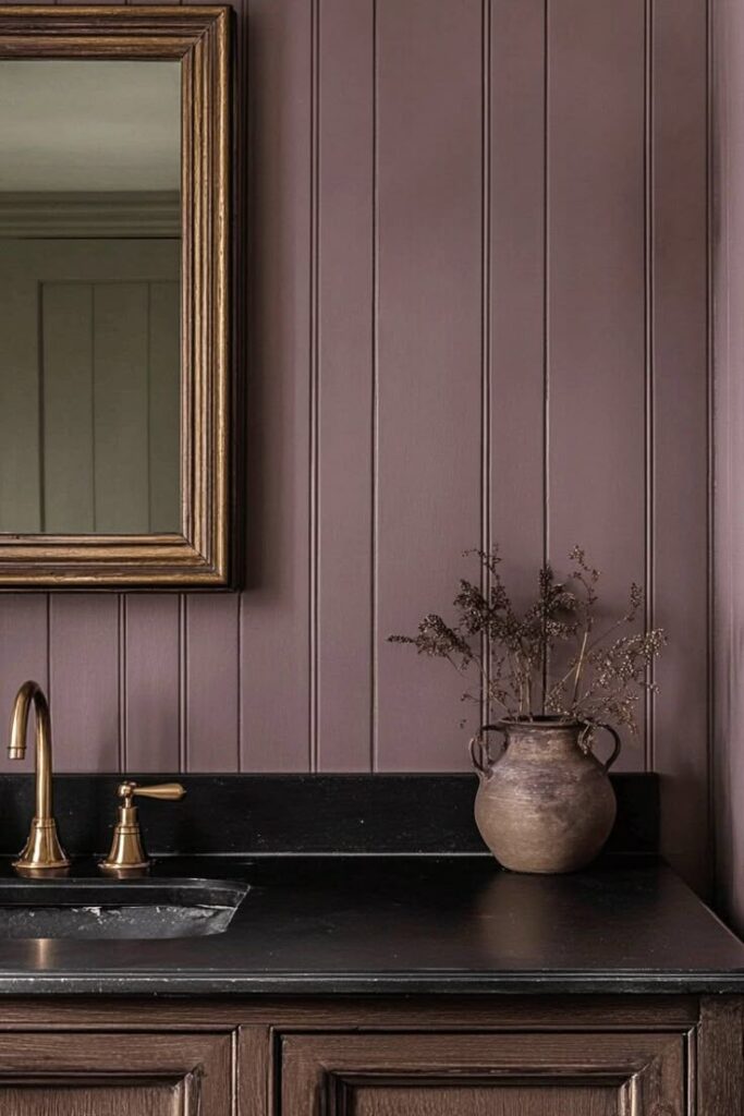 Elegant bathroom with rustic charm: brown panel wall, bronze faucet, antique mirror, pottery vase. Cozy, vintage interior decor.