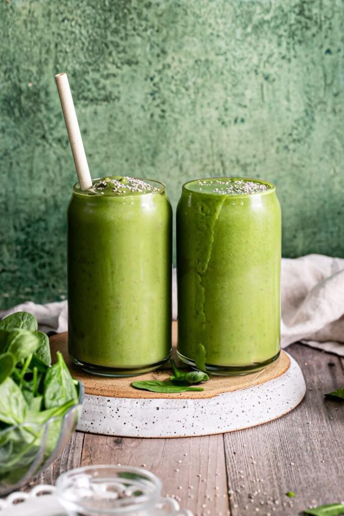 Refreshing green smoothies with spinach and chia seeds in glass jars on a wooden table. Healthy vegan drink concept.