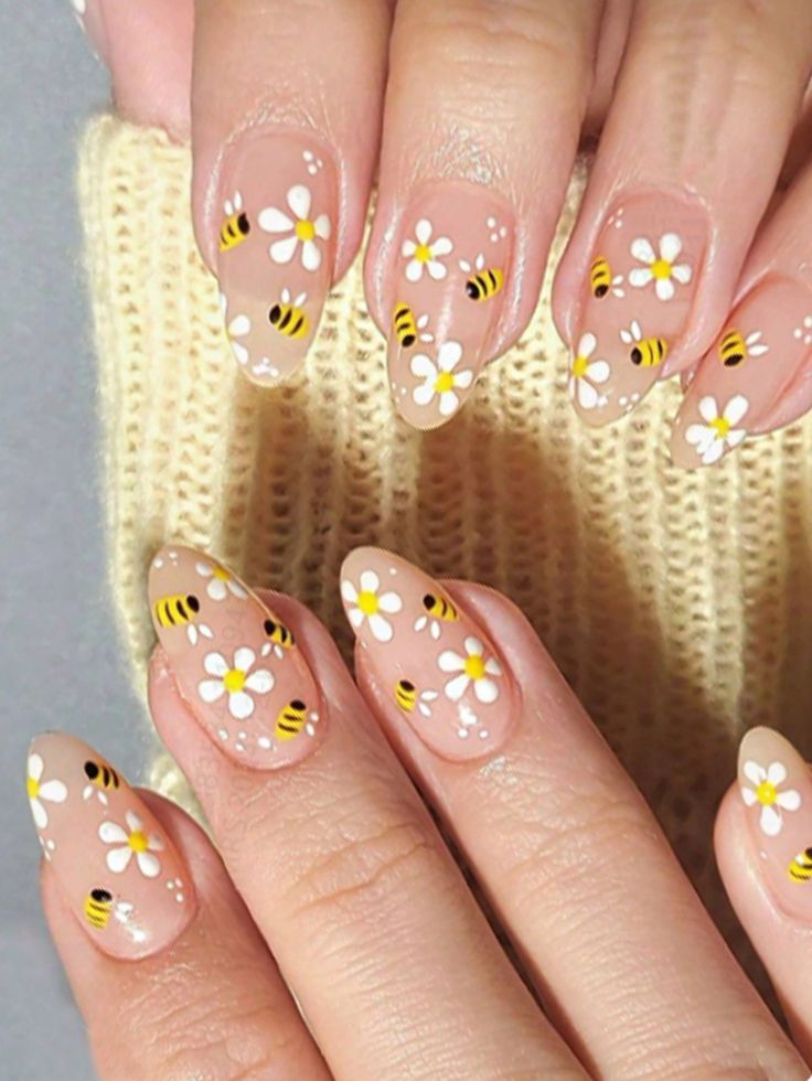 Bee and daisy nail art design on almond-shaped nails, featuring delicate hand-painted flowers and bees on a neutral background.