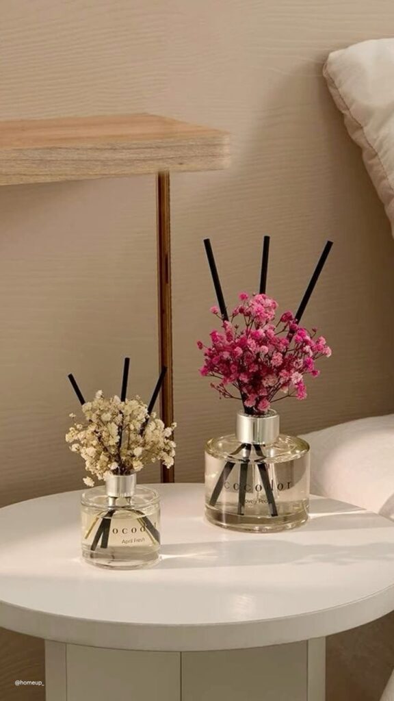 Elegant reed diffusers with pink and white flowers on a round table, adding a touch of sophistication to modern home decor.