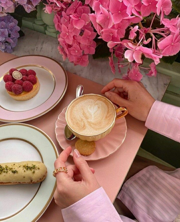 Cappuccino and desserts on a pink table with vibrant pink flowers. Elegant cafe setting, perfect for a cozy coffee break.