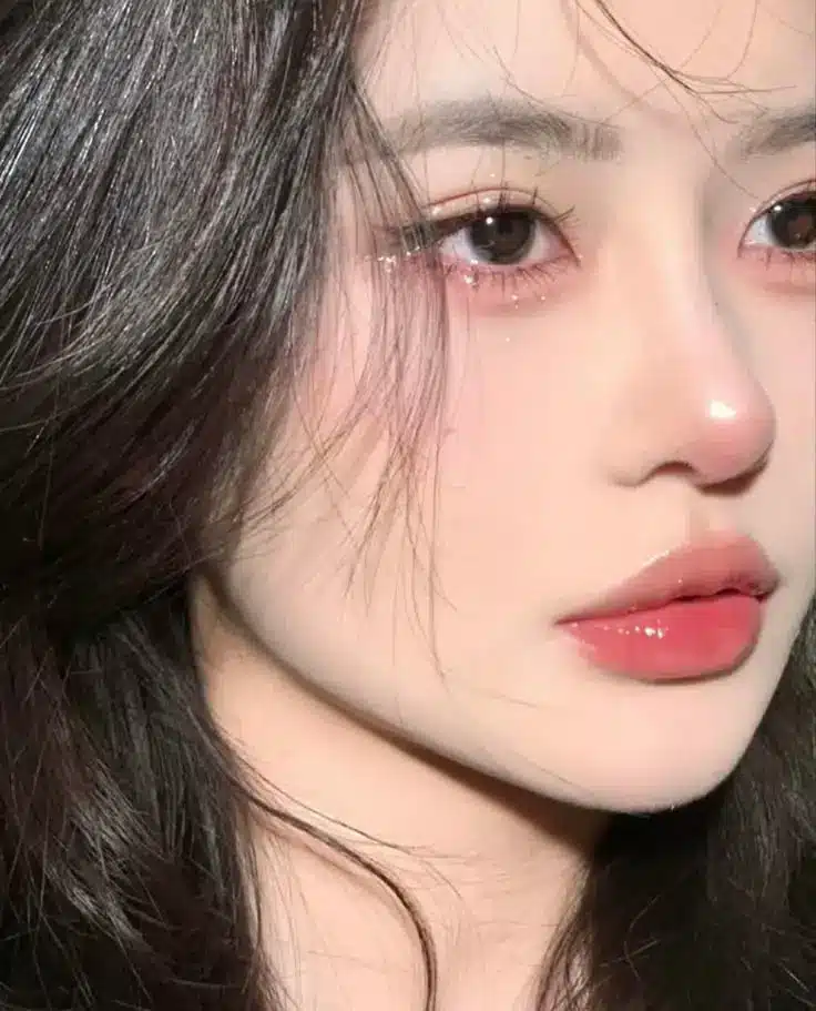 Close-up of a young woman's face with glossy lips, smooth skin, and dark hair, showcasing beauty and skincare.