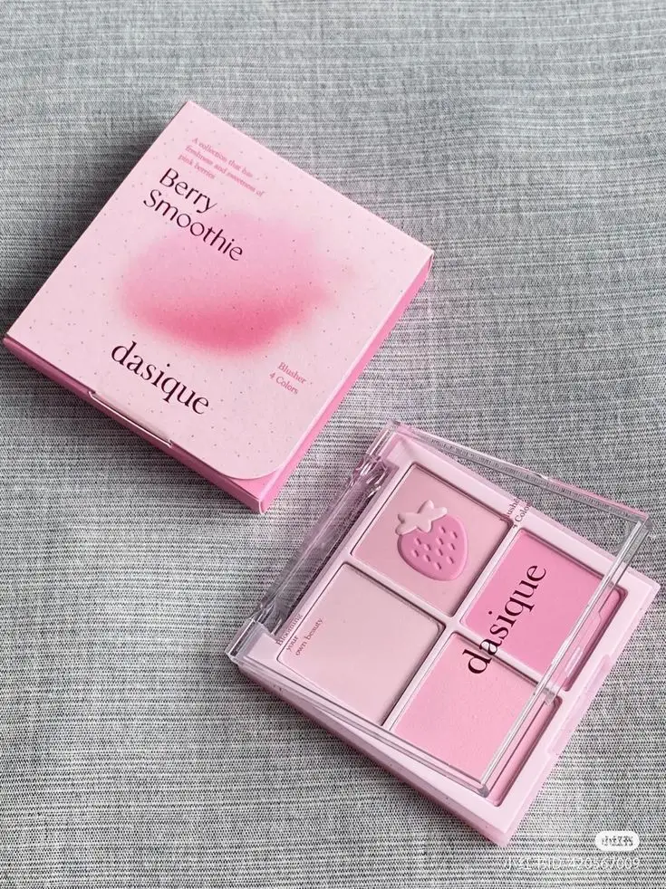 Dasique Berry Smoothie Blusher palette on fabric background, featuring pink shades and cute strawberry design on compact.
