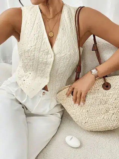 Fashionable woman in white crochet top with a straw bag, accessorized with jewelry, embodies chic summer style.