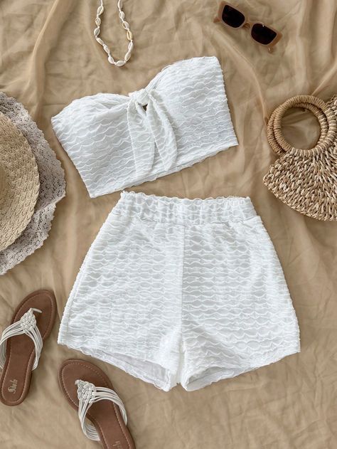 White lace summer outfit with matching crop top and shorts, surrounded by sandals, sunglasses, hats, and a woven bag. Perfect beachwear.