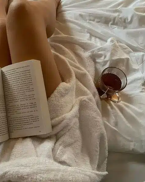 Cozy morning in bed with a book and a cup of tea, wrapped in a soft blanket. Relaxation and comfort on a peaceful day.