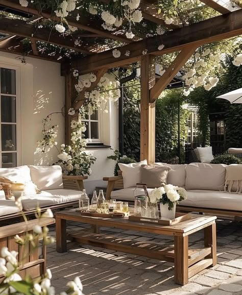 2b2c657742c503f8d266d98ba5c62842 - Handy Home Cozy outdoor patio with wooden pergola, white sofas, floral decor, and wooden coffee table, perfect for relaxing gatherings.