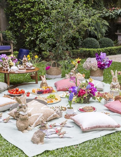 2b521f1bb0cfb30e62ad84b90be5ccf1 - Handy Home Outdoor picnic setup with decorative bunnies, colorful flowers, and an assortment of dishes on a garden lawn.