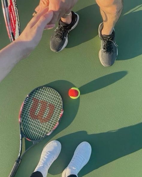 People shaking hands on a tennis court with rackets and ball nearby. Sport, friendship, and teamwork concept.