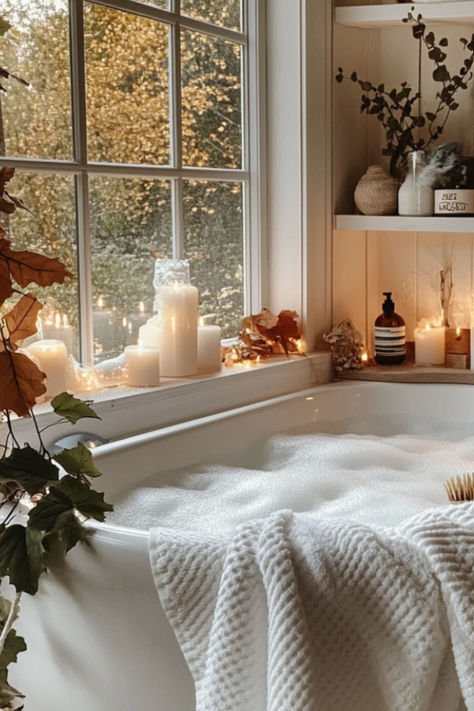 Cozy bubble bath in a white tub by a window, surrounded by candles and autumn decor, creating a warm and relaxing atmosphere.