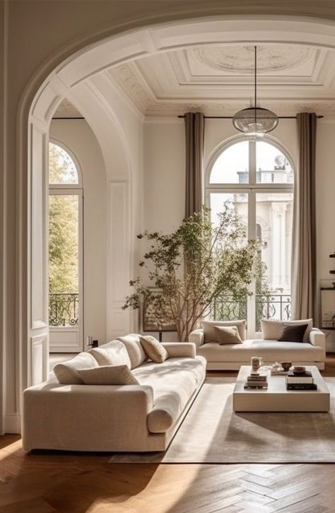 6d783156649134a918a58da5c695ac55 - Handy Home Elegant living room with high ceilings, large windows, neutral couches, and a central coffee table, bathed in natural light.