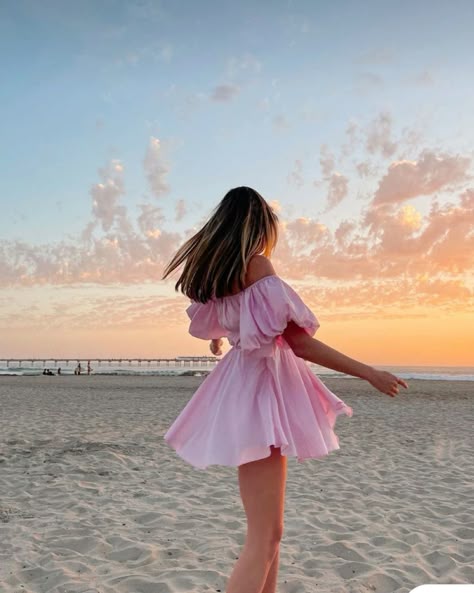729b01c98b4e16444ae77782718d8193 - Handy Home Woman in pink dress twirling on beach at sunset, with colorful sky and ocean backdrop. Perfect summer evening scene.