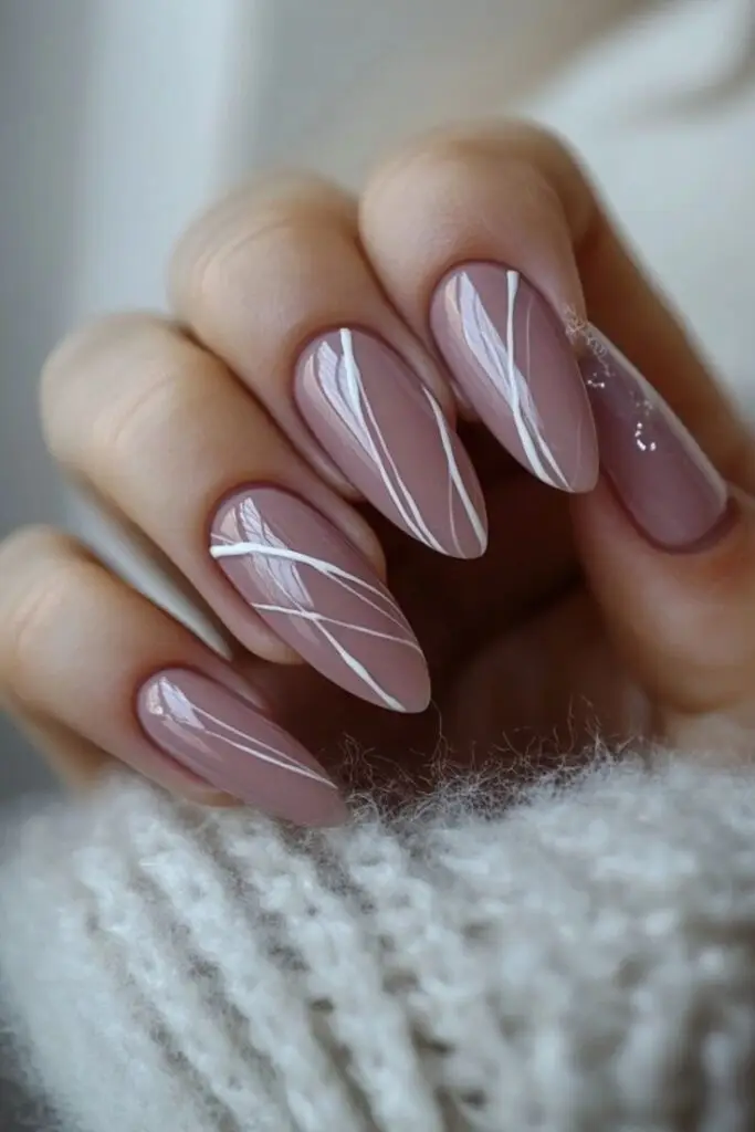 Elegant almond-shaped nails with nude polish and white line accents, perfect for a chic, minimalist manicure.