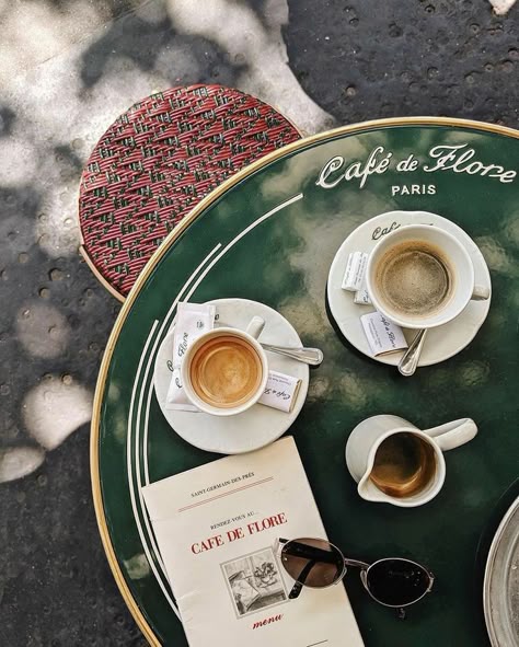 Parisian café table with coffee cups and a menu at Café de Flore, on a shaded outdoor patio.
